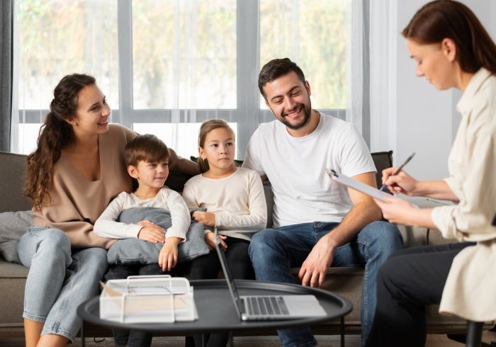 Family smiling in front of a therapist writing
