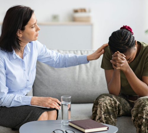 A woman therapist comforting a woman soldier with complex PTSD